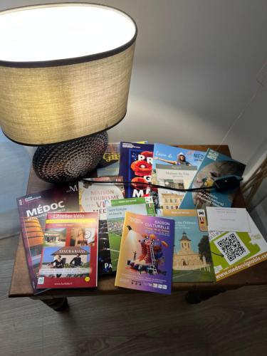 a pile of books on a table next to a lamp at Le figuier in Saint-Sauveur