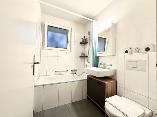 a white bathroom with a sink and a toilet at Modern & Central Apartment - Zurich Oerlikon in Zürich