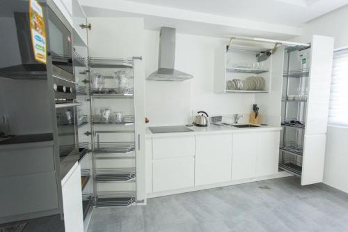 a kitchen with white cabinets and stainless steel shelving at Accra Luxury Apartments at Lul Water in Accra