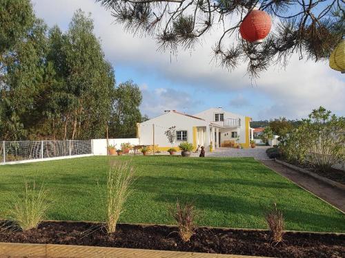 a white house with a yard with a green lawn at Quinta da Familia in Caldas da Rainha