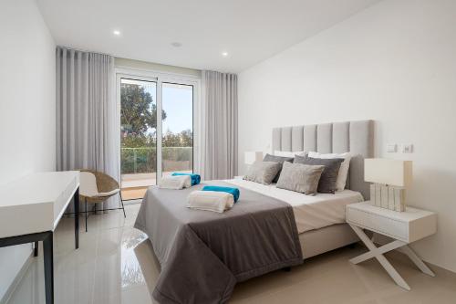 ein weißes Schlafzimmer mit einem großen Bett und einem Schreibtisch in der Unterkunft Ancora Apt do Mos in Lagos