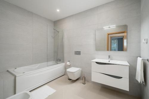 ein weißes Badezimmer mit einer Badewanne, einem WC und einem Waschbecken in der Unterkunft Ancora Apt do Mos in Lagos