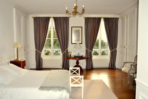 a bedroom with a bed and a table and windows at Clos de Bellefontaine B&B in Bayeux