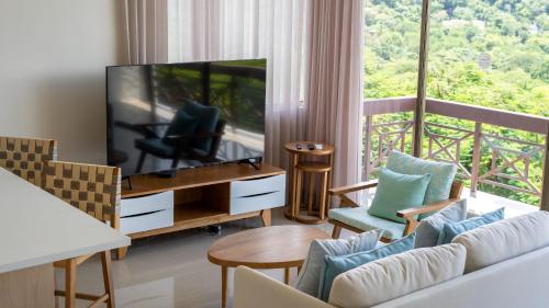 a living room with a television and a balcony at Breeze and Sunset at Playa Hermosa in Playa Hermosa
