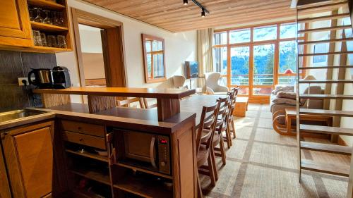 una cucina con un bancone e un tavolo con sedie di Appartement Premium à Flaine, altitude 1740 m, 8 à 10 personnes, au pied des pistes, piscine, jacuzzi, sauna, hammam et salle de sport a Flaine