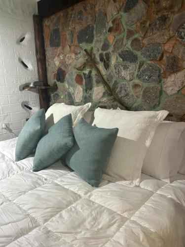a bed with pillows on it with a stone wall at La Cabaña del Abuelo in Lourdes