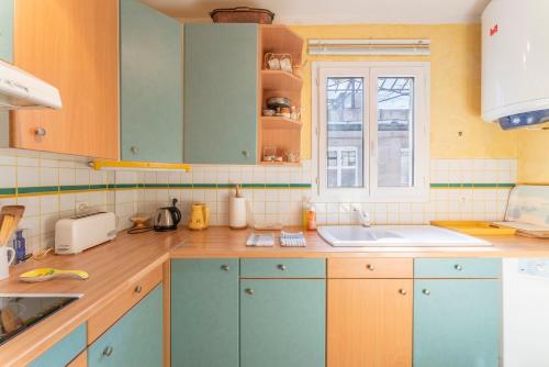 a kitchen with blue cabinets and a sink and a window at Appart face au Palais des Papes in Avignon