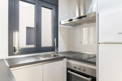 a white kitchen with a sink and a window at Apartamentos Bellamar in Barbate
