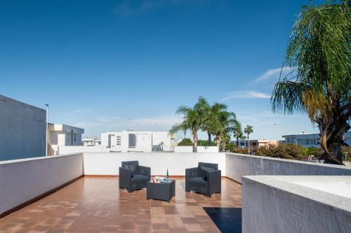 a balcony with black chairs and palm trees at Villetta Panoramic Rooftop San Foca in San Foca