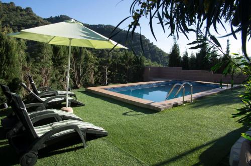a pool with chairs and an umbrella and a swimming pool at Rural Montes Málaga: Finca Pedregales in Málaga