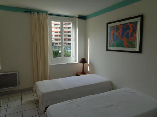 une chambre d'hôtel avec deux lits et une fenêtre dans l'établissement Croisette-Oasis, à Cannes