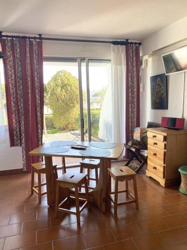 une table et des chaises dans une pièce avec une fenêtre dans l'établissement AS21558- Studio cabine dans une résidence de standing direct sur plage sud, au Grau-du-Roi