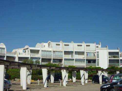 un bâtiment blanc avec des voitures garées dans un parking dans l'établissement AS21558- Studio cabine dans une résidence de standing direct sur plage sud, au Grau-du-Roi