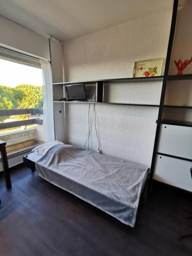 une petite chambre avec un lit et une fenêtre dans l'établissement AS21549 - Studio lumineux vue mer avec piscine et parking commun, au Grau-du-Roi