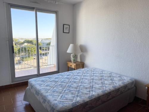 une chambre avec un lit et une grande fenêtre dans l'établissement AS21543 - P2 double cabine avec double terrasse vue mer et parking privé, au Grau-du-Roi