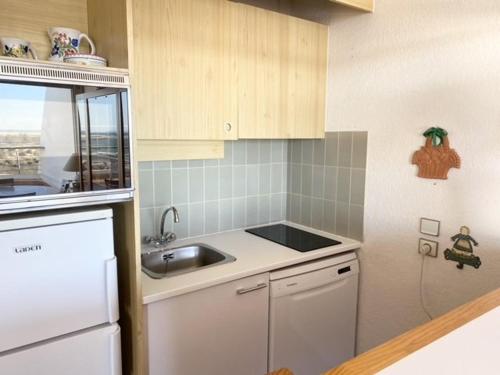 une petite cuisine avec un évier et un réfrigérateur dans l'établissement AS21543 - P2 double cabine avec double terrasse vue mer et parking privé, au Grau-du-Roi