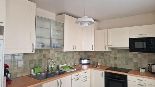 une cuisine avec des armoires blanches et un évier dans l'établissement Thiais large apartment near ORLY PARIS 4 à 6 personnes, à Thiais