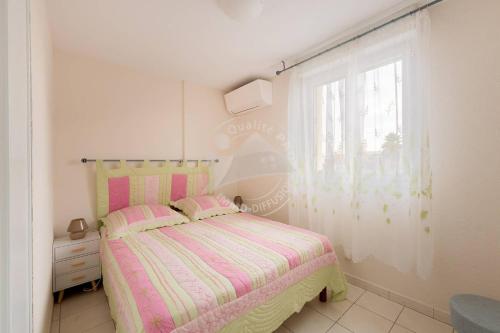 - une chambre avec un lit rose et jaune et une fenêtre dans l'établissement AS21493 - Villa P3 avec terrasse et solarium, au Grau-du-Roi