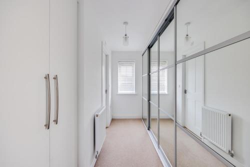 a corridor of a room with white walls and mirrors at Stunning Detached House with Driveway Parking, Office Room, Self-Check-In, Fast WiFi and Smart TV with Sky and Netflix by Yoko Property in Milton Keynes