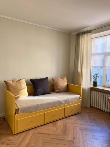 - un lit jaune dans une chambre avec fenêtre dans l'établissement Brand new apartment in a historical location, à Riga