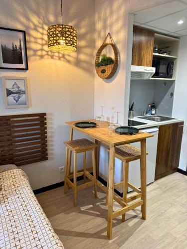 une cuisine avec une table en bois et deux tabourets dans l'établissement Le Montagnard - Wifi - Clim - Chaleureux, à Lourdes