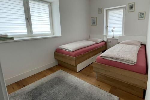 two beds in a room with two windows at Apartments Griesser - Included BrixenCard and parking garage in house in Bressanone