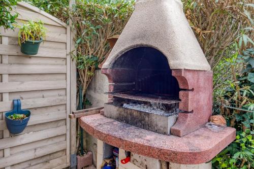 a brick oven in a garden with two potted plants at Maison pour 6 entre Vignes et Mer in Marseillan