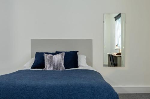 a bed with a blue blanket and a mirror at For Students Only Radford Mill in Nottingham in Nottingham