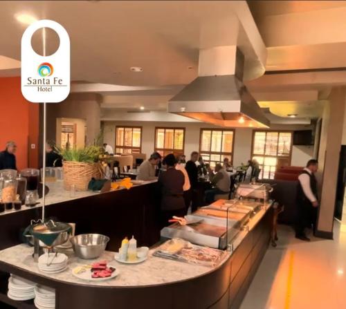 a restaurant with a counter with people standing around it at Hotel Santa Fe in Camargo