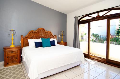 a bedroom with a bed with white sheets and blue pillows at Casa Amor Por Siempre in Bucerías