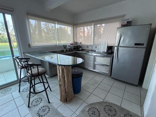 a kitchen with a table and a refrigerator at Acogedor depto Acapulco Diamante frente a campo de Golf Vidanta in Acapulco