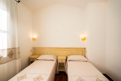 two beds in a small room with white walls at Borgo Degli Ulivi in Àrbatax