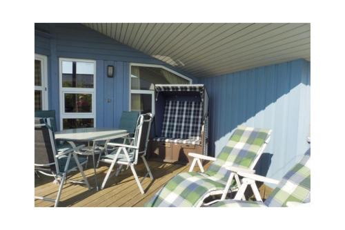 a porch with a table and chairs on a deck at Ferienhaus Ty Glaz in Wesselburenerkoog
