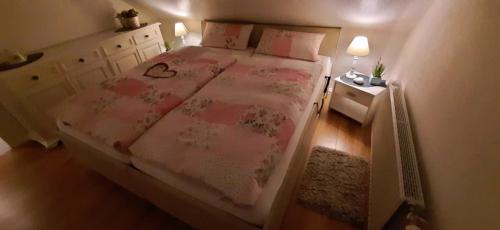 une chambre avec un grand lit avec des draps et des oreillers roses dans l'établissement Ferienwohnung Neumann, à Wesselburen