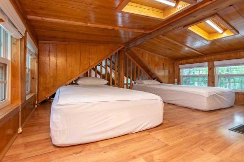 two beds in a room with wooden walls and wood floors at Port of Kimberling Resort & Campground in Kimberling City