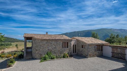 a stone house with a garage and mountains in the background at Maison Time-out in Villevieille