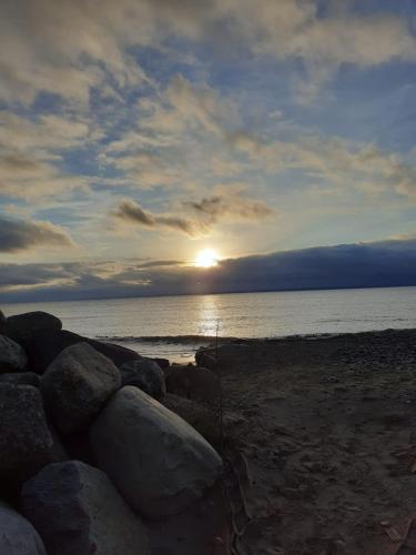 a sunset over the ocean with rocks on the beach at Oaza spokoju in Jastrzębia Góra