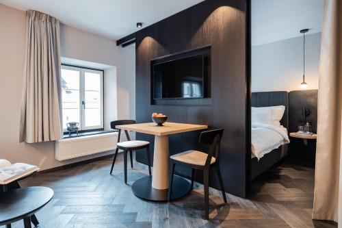 a hotel room with a bed and a table and chairs at Schwarzer Adler - Concept Living in Vipiteno