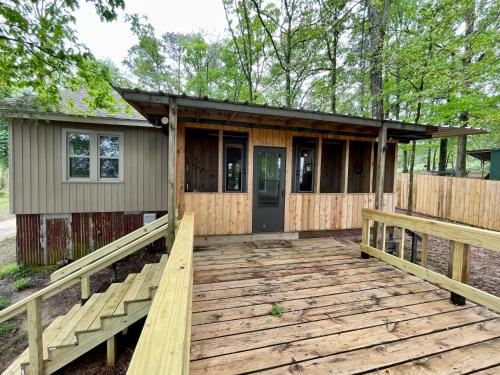 una pequeña casa con una terraza de madera delante de ella en The Pelicans Nest, en Farmerville