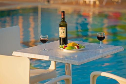 a bottle of wine and two glasses on a table next to a pool at Enastron Villas in Kyparissia