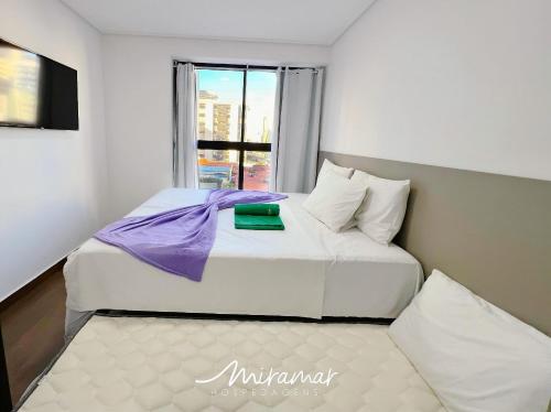 a bedroom with a white bed with a window at Move - Tambaú in Tambaú