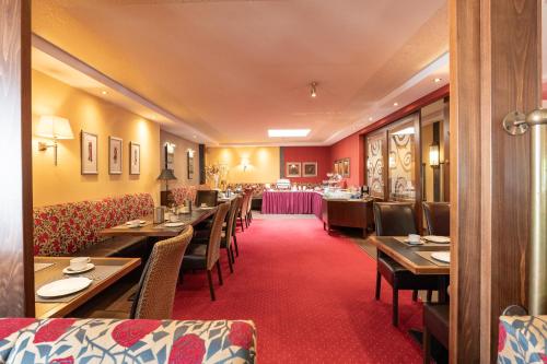 een restaurant met houten tafels en stoelen en een rode loper bij Dagstuhler Hof in Wadern