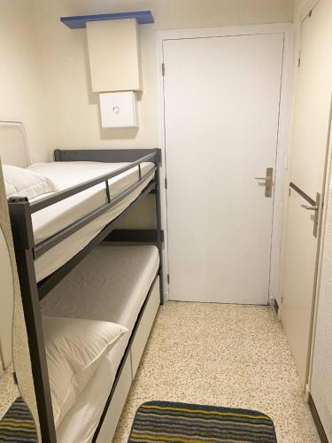 Cette petite chambre comprend 2 lits superposés et une porte. dans l'établissement AS21515 - Studio cabine avec joli jardin et parking privé, au Grau-du-Roi