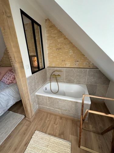 La salle de bains est pourvue d'une baignoire à côté d'un lit. dans l'établissement Le corps de Ferme et la Grange à Chassagne, à Saint-Amand-de-Coly