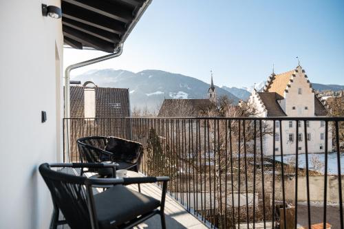 a balcony with a chair and a view of a city at Schwarzer Adler - Concept Living in Vipiteno