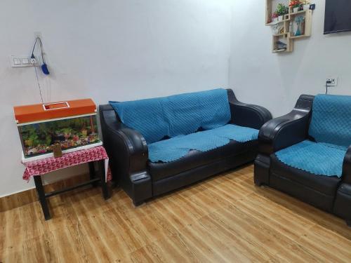 a living room with two couches and a fish tank at Aashiana in Jhūsi