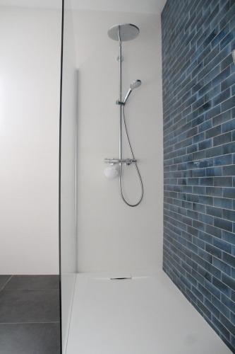 La salle de bains est pourvue d'une douche et d'un mur en briques. dans l'établissement Villa Wax - Pool & Surf, à Santec