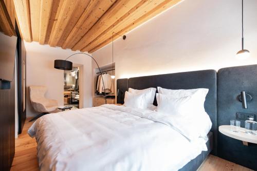 a bedroom with a large white bed and a desk at Schwarzer Adler - Concept Living in Vipiteno