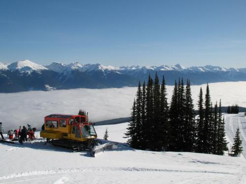 a yellow and red truck on top of a snow covered mountain at Mica Mountain Lodge & Log Cabins in Tete Jaune Cache