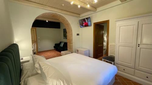 a bedroom with a white bed and a living room at Ca' Virginia Country House Wellness in Montecalvo in Foglia